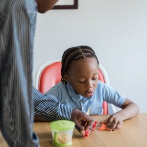 A mother and daughter enjoying playtime with toys at a table indoors.